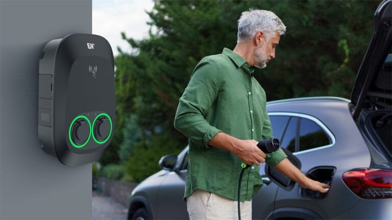 A man is holding a charging gun and charging an EV